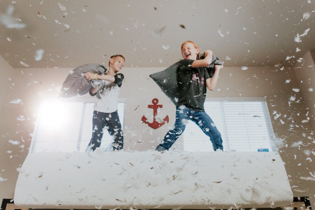 Two middle age children in a pillow fight.