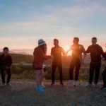 A group of teens gathered, laughing at sunset.