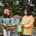 Ethnic mother talking to daughter with gardening tools