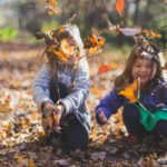 Two young children playing in the leaves.