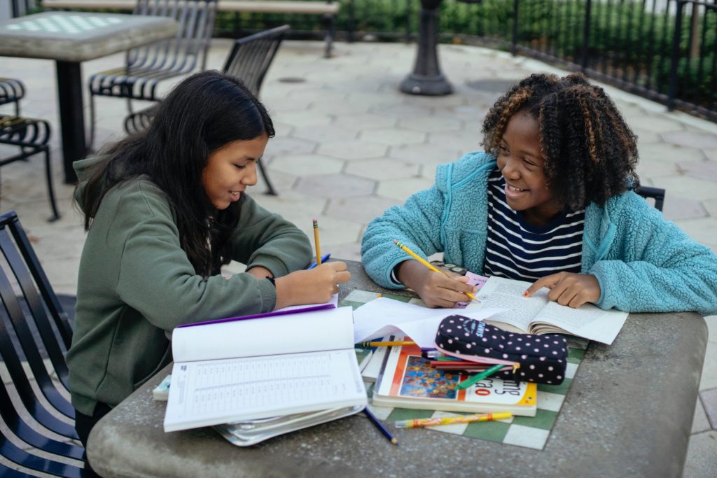 cheerful multiethnic little girls doing homework together