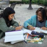 cheerful multiethnic little girls doing homework together