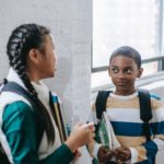 Positive diverse schoolchildren standing in corridor and talking