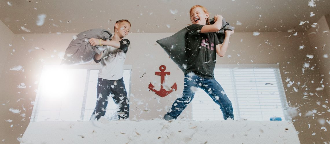 Two middle age children in a pillow fight.