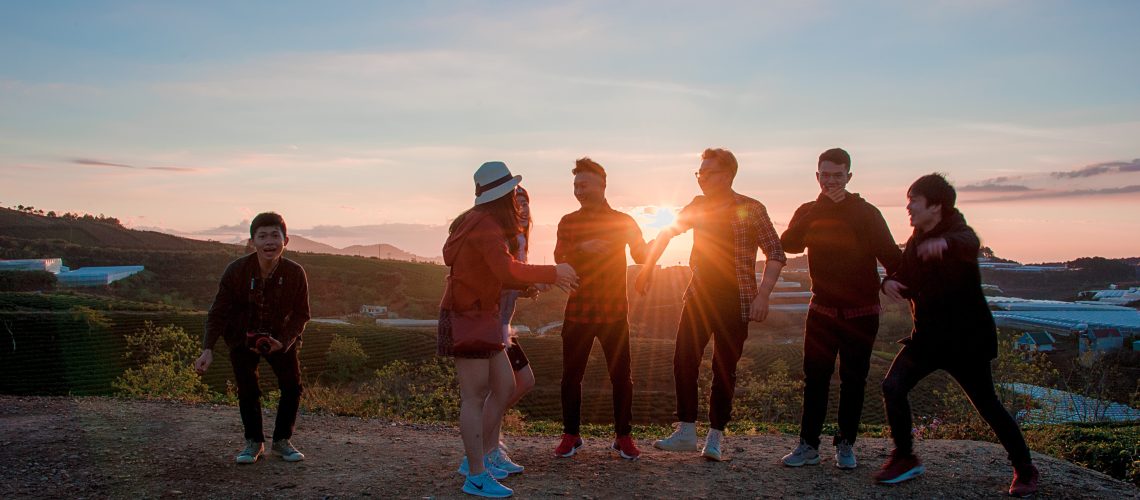 A group of teens gathered, laughing at sunset.